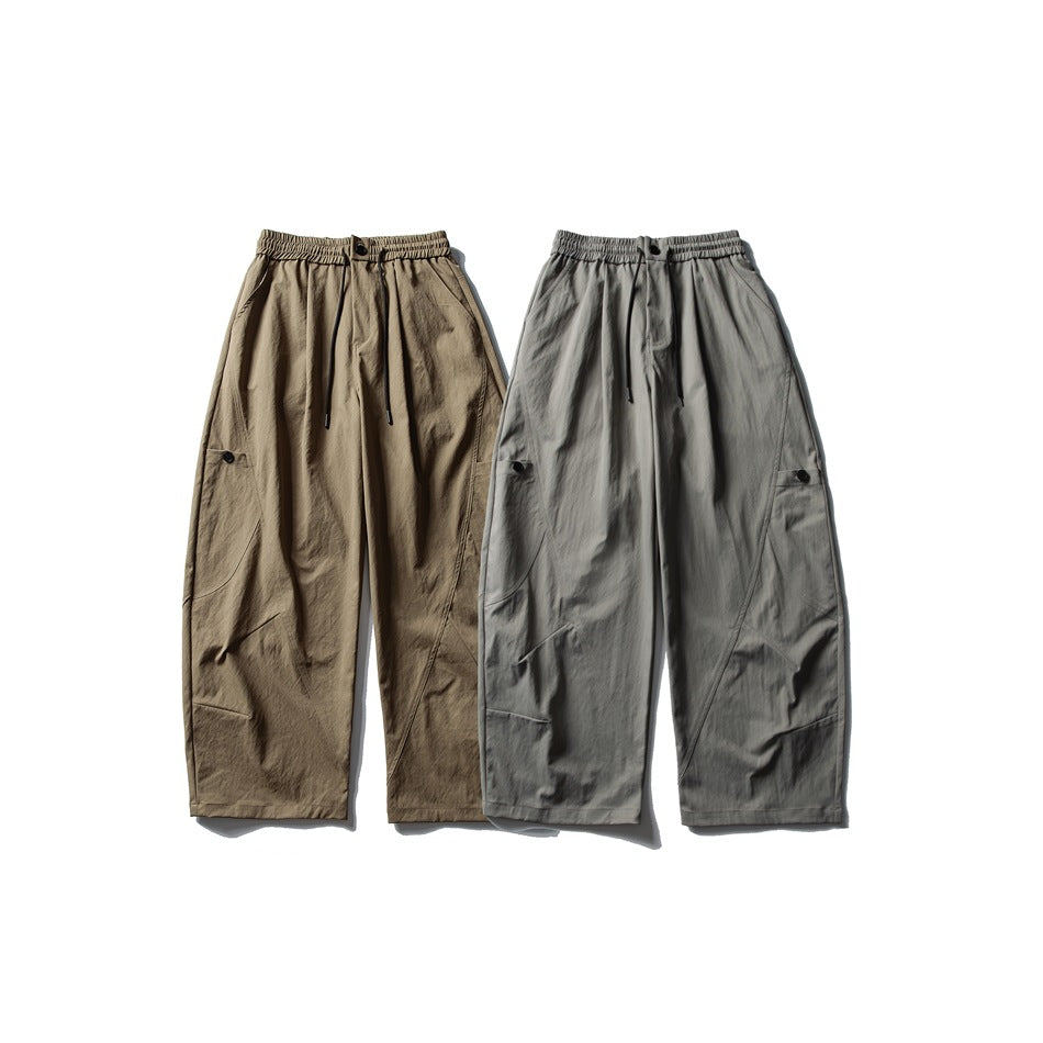 Two pairs of wide-leg trousers laid flat, one khaki and one gray, with elastic drawstring waists and utility pockets.