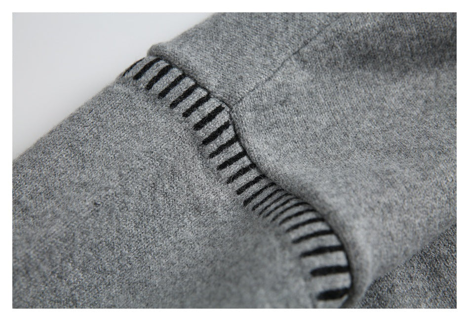 Gray sweater detail with black ladder-like stitching tracing a curved seam.
