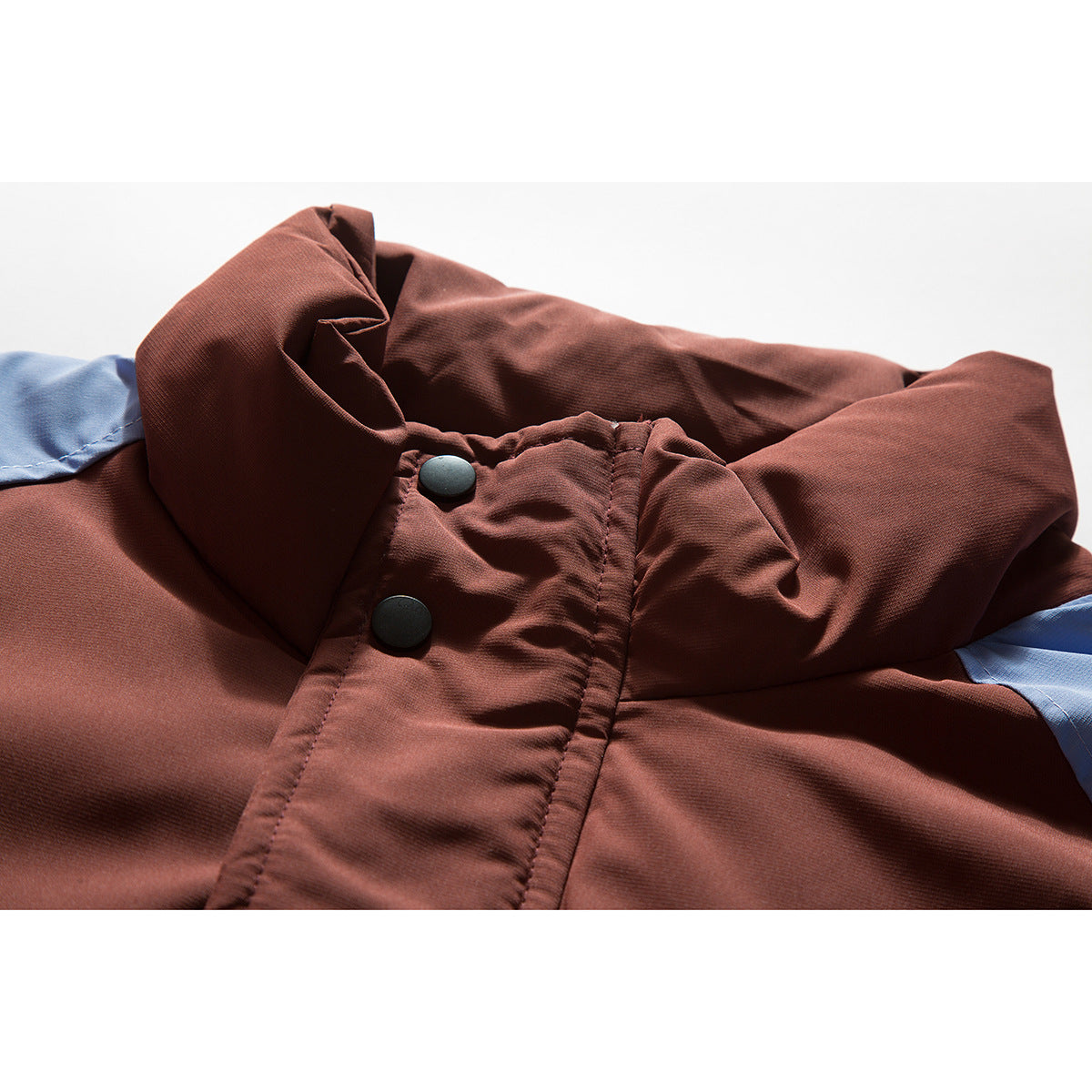 Close-up of a rust-brown jacket collar and snap-button placket with light blue contrast panels.