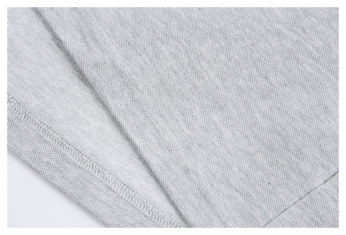 Close-up of light gray knit fabric showing an inside seam and overlock stitching.