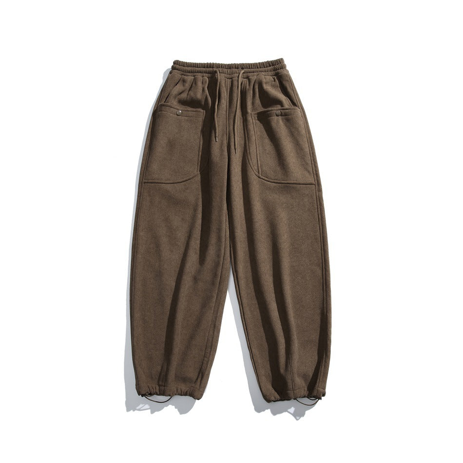 Front view of brown jogger pants with an elastic drawstring waist, large buttoned patch pockets, and elastic cuffs.