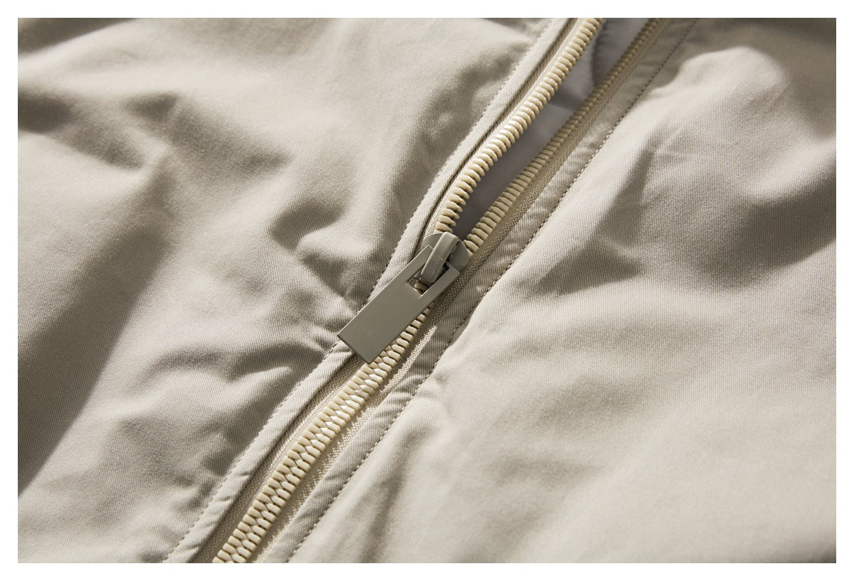Close-up of the beige jacket's front zipper and pull.