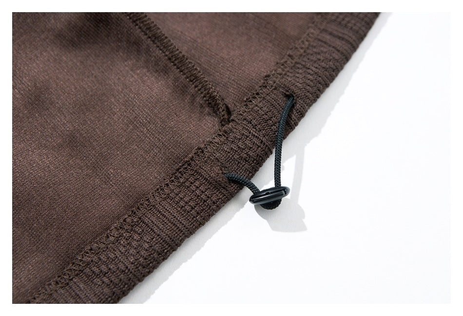 Close-up of a dark brown garment edge with stitched trim and a black drawcord toggle.