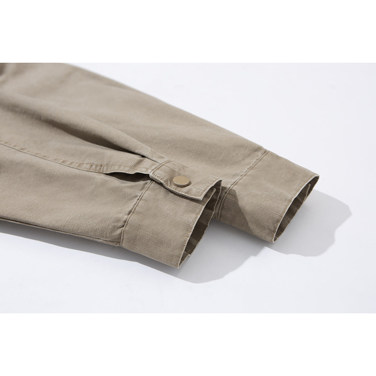 Close-up of a taupe jacket sleeve cuff with a snap-tab closure.