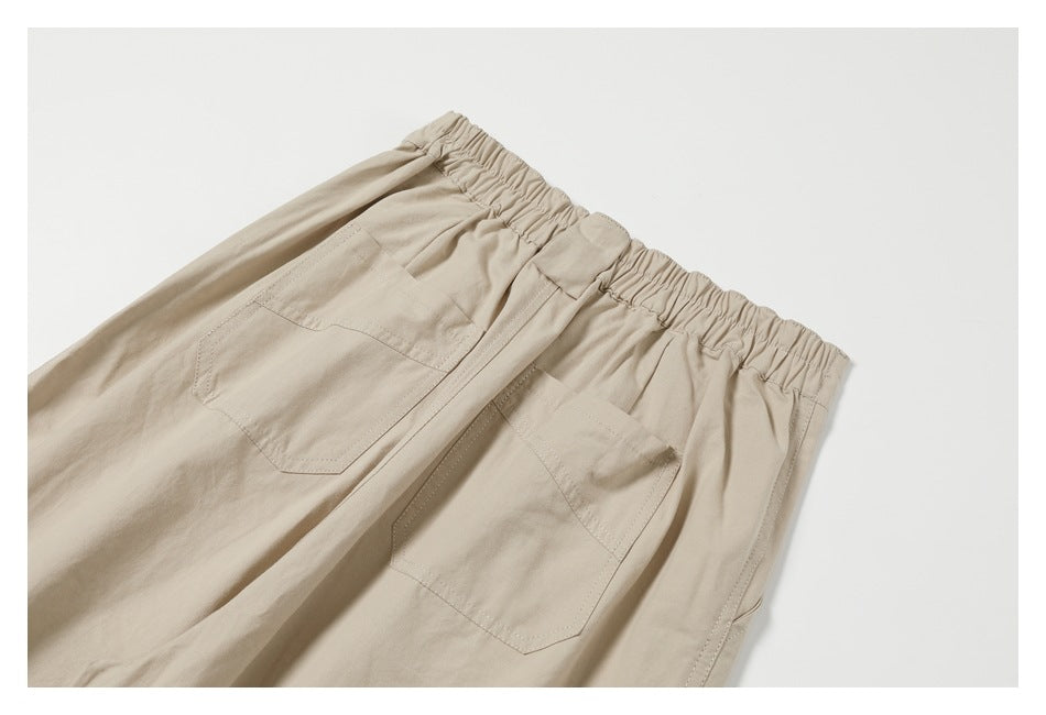 Partial rear view of beige trousers with an elastic waistband and two patch pockets.