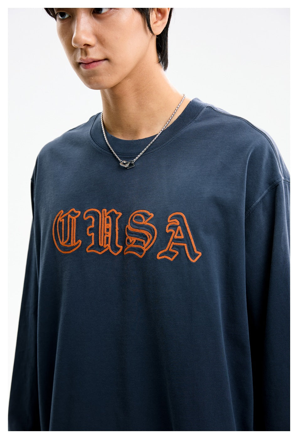 Close-up of the navy shirt's crew neck and orange outlined chest lettering.