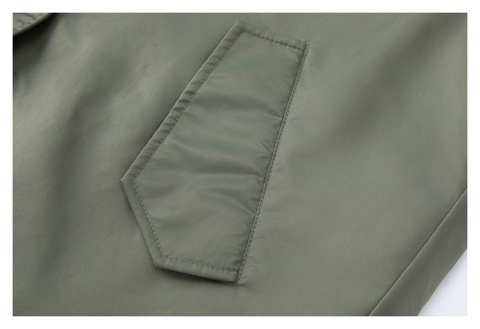 Close-up of a stitched patch pocket on olive-gray fabric.