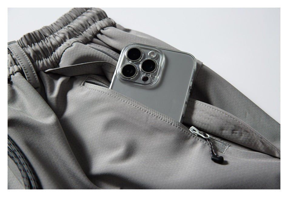 Close-up of gray pants with a zippered pocket holding a phone.