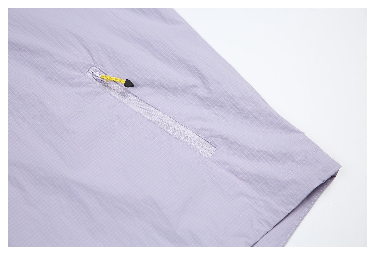Close-up of a diagonal zipper with a yellow pull on lavender grid-patterned fabric.