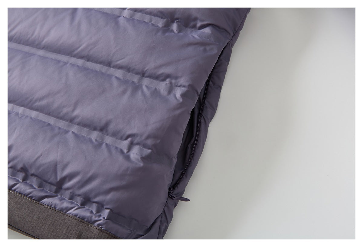 Close-up of the jacket's quilted side edge with a dark zipper and contrast hem band.