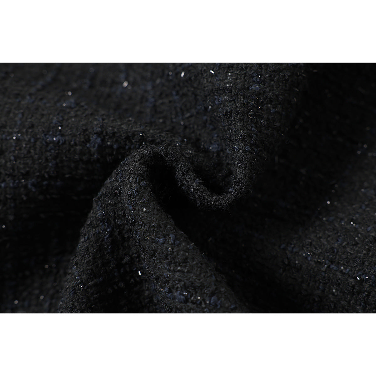 Macro view of folded black textured fabric showing its raised, flecked surface.
