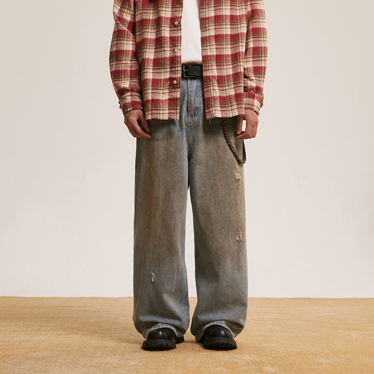 Model wearing loose gray washed jeans with small distressed patches, shown from the front.