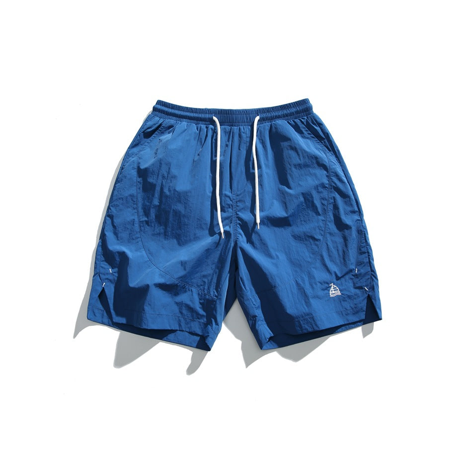 Lake blue knee-length shorts with elastic waist, white drawstring, and small embroidered sailboat, flat lay front view