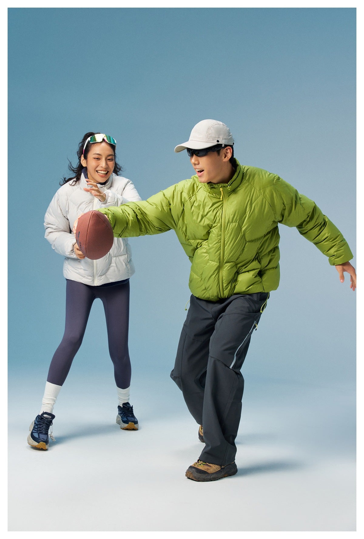 Two models wearing white and lime-green quilted jackets play with a ball; the green jacket is prominent.