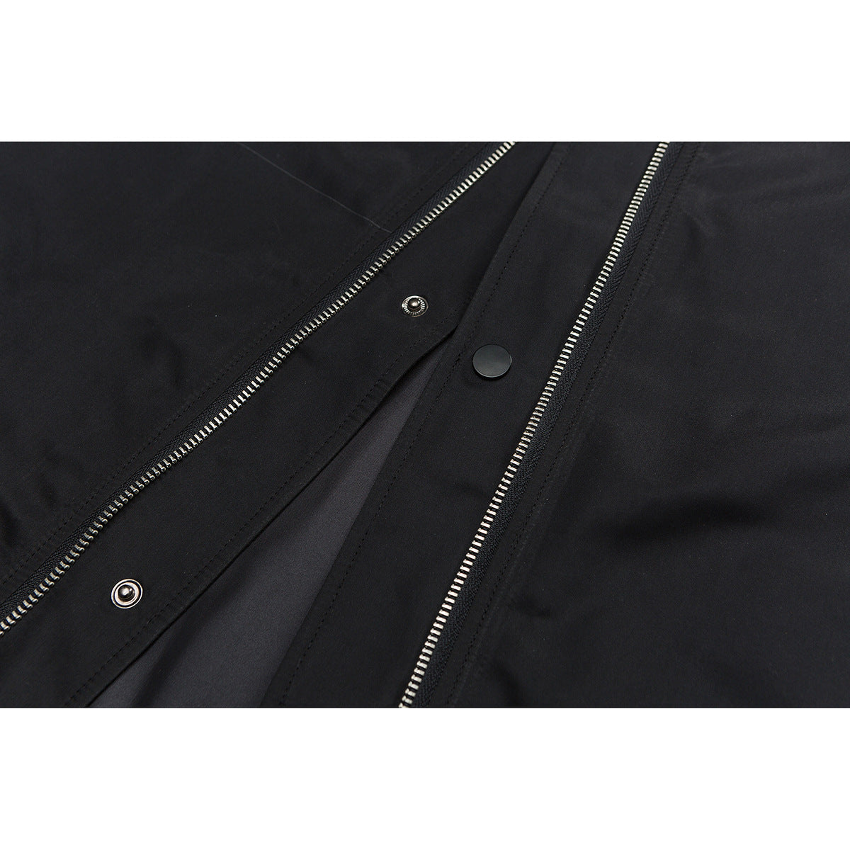 Close-up of a black jacket's front closure with silver zippers and snap fasteners.