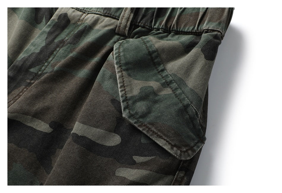 Close-up of a flap pocket and waistband on green, brown, and black camouflage trousers.