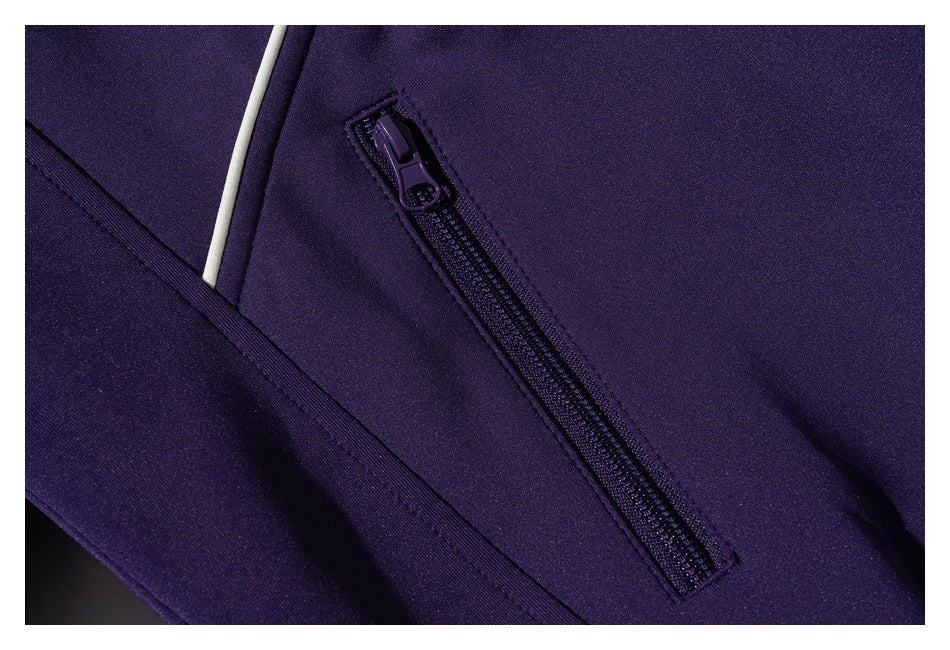 Close-up of a dark purple garment with a diagonal zippered pocket and narrow white piping.