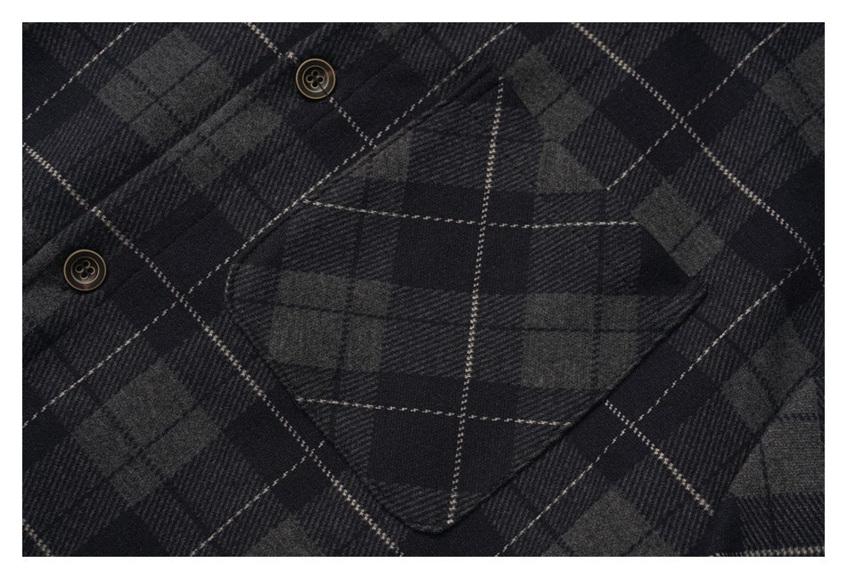 Close-up of a buttoned chest pocket on the charcoal and black plaid shirt.