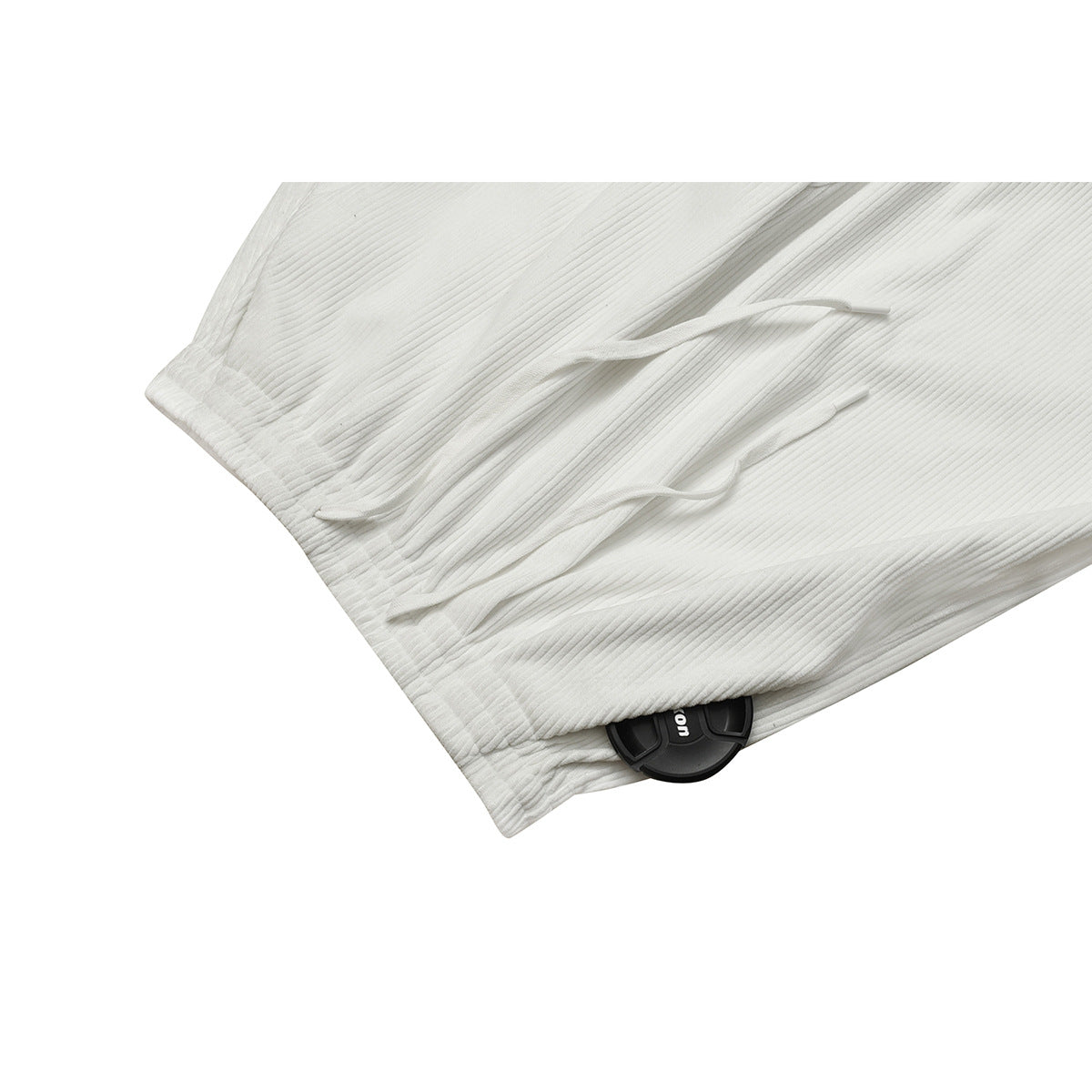 Close-up of white ribbed pants showing the gathered waistband and two white drawstrings.