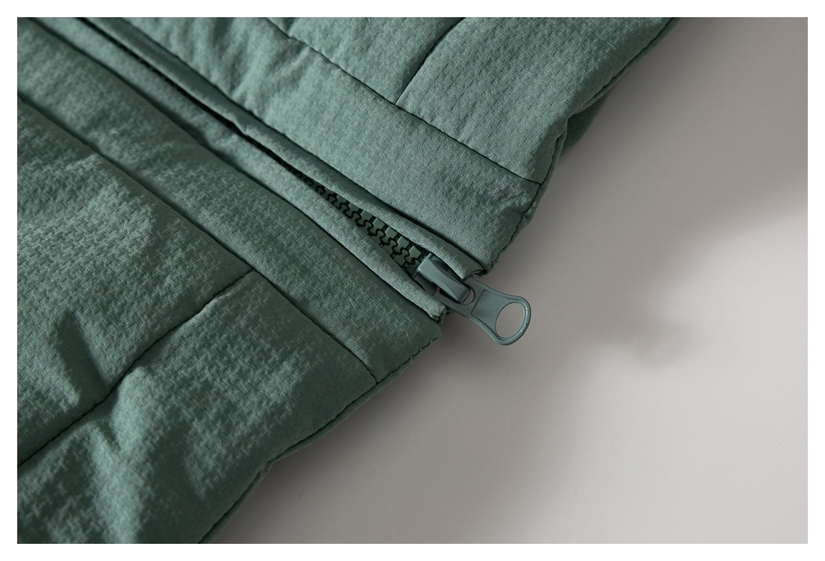 Close-up of the lower end of the jacket's front zipper and textured sage-green panels.