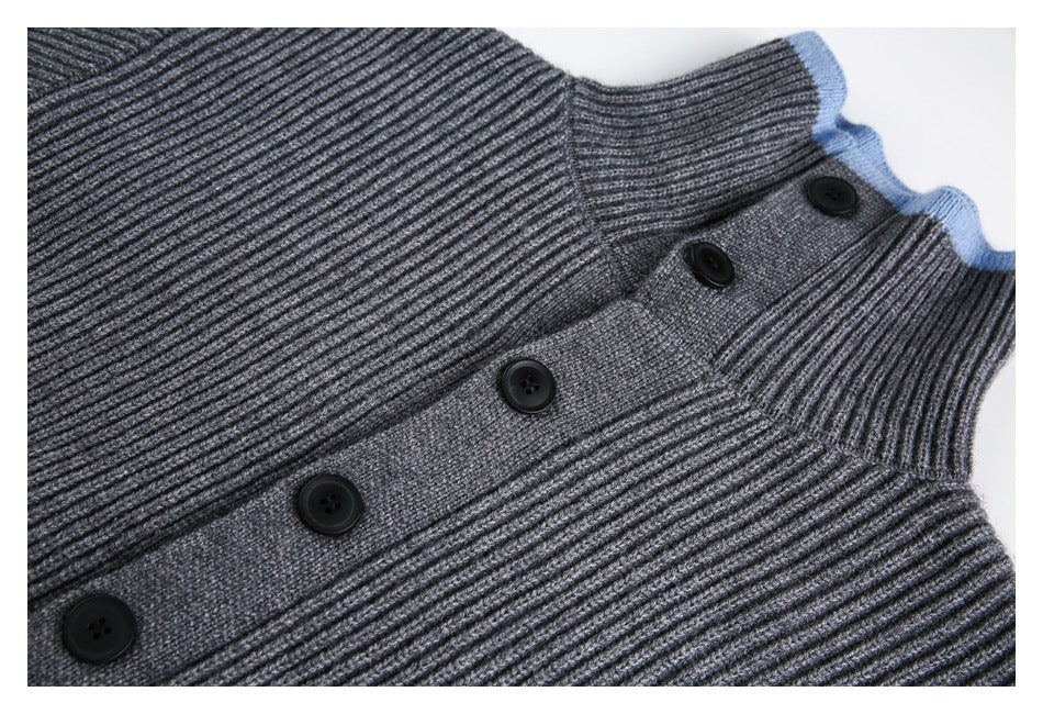 Close-up front view of a gray ribbed sweater with a high collar, blue trim, and black-button placket.