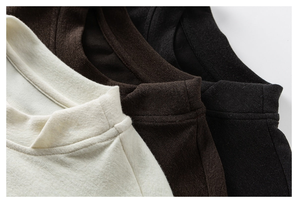 Close-up of cream, dark brown, and black tops arranged together, showing their rounded necklines.
