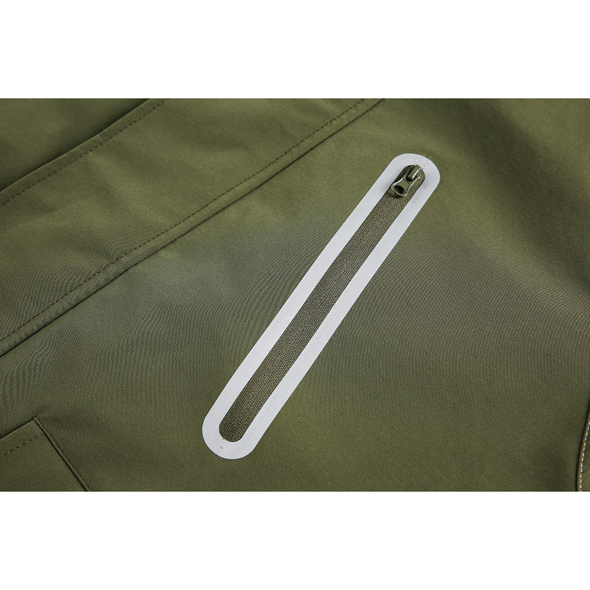 Close-up of an olive jacket's long zipper with a white border and a small metal pull.