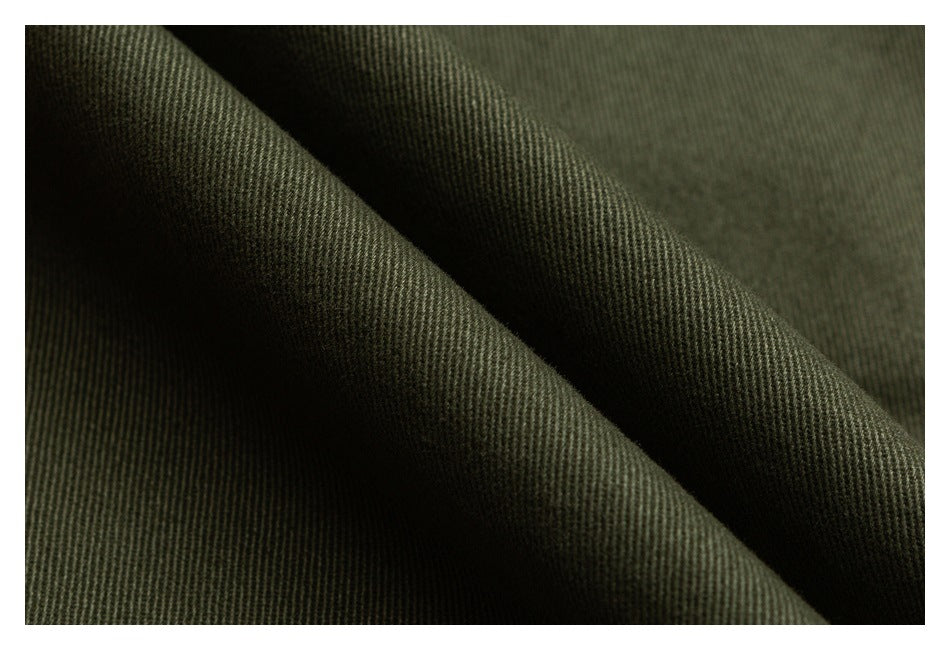 Extreme close-up of dark olive fabric folds, showing the diagonal weave texture.
