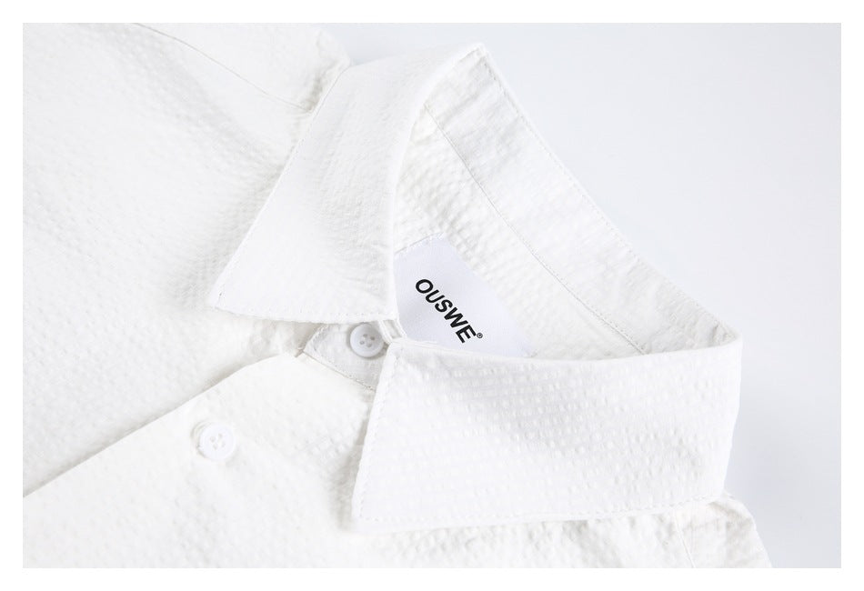 Close-up of the white shirt's collar, buttons, textured surface, and neck label.