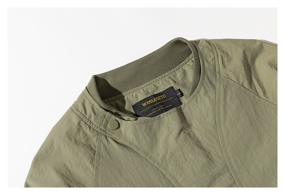 Close-up of an olive jacket's stand collar, snap closure, overlapping front panel, and sewn-in neck label.