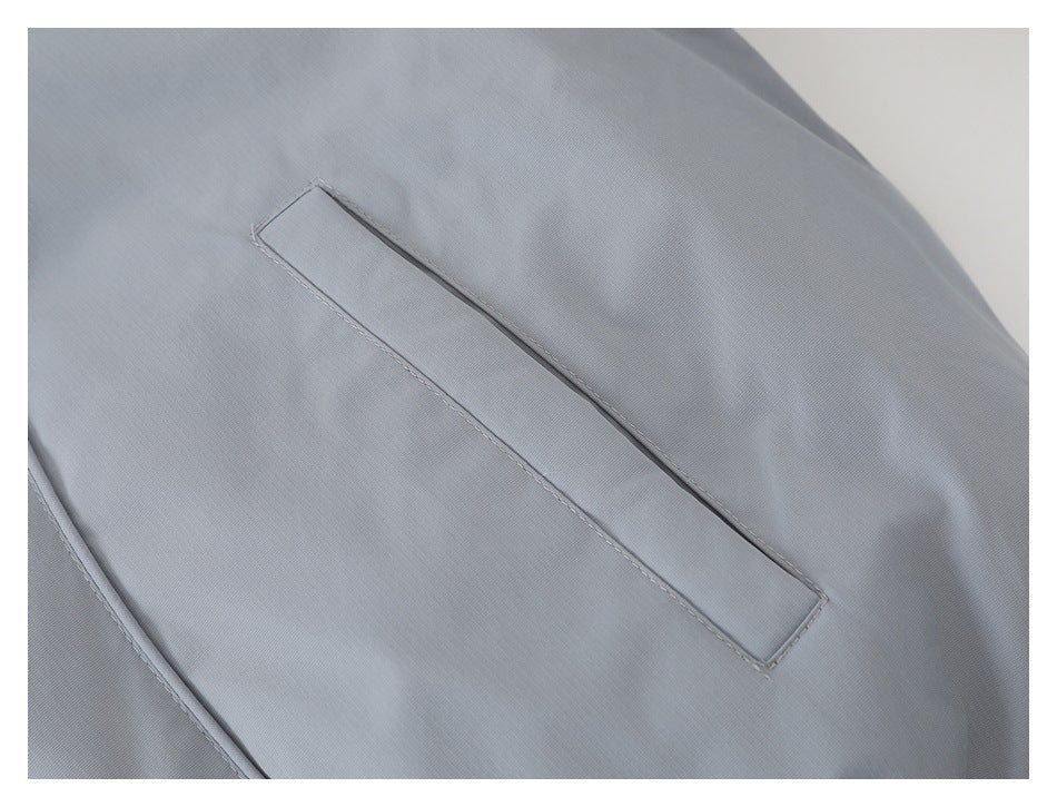 Close-up of a narrow welt pocket on the light gray-blue jacket.