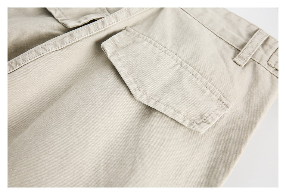 Close-up of light beige trousers showing a small flap pocket, belt loops, and waistband stitching.