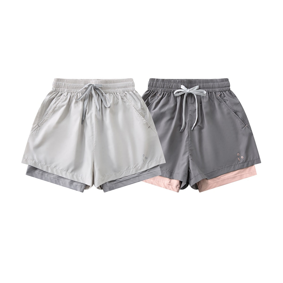Two pairs of layered athletic shorts shown from the front in white and gray colorways, with elastic waists and drawstrings.