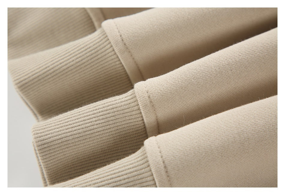 Close-up of beige sweatshirt sleeves with ribbed cuffs and stitched cuff edges.