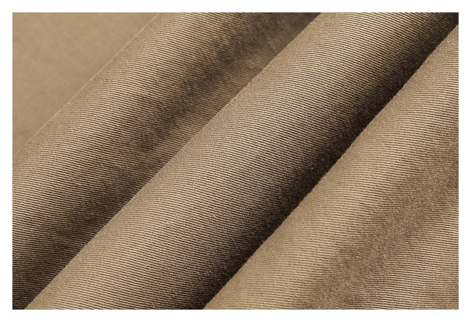 Close-up of folded tan trouser fabric showing its fine diagonal weave.