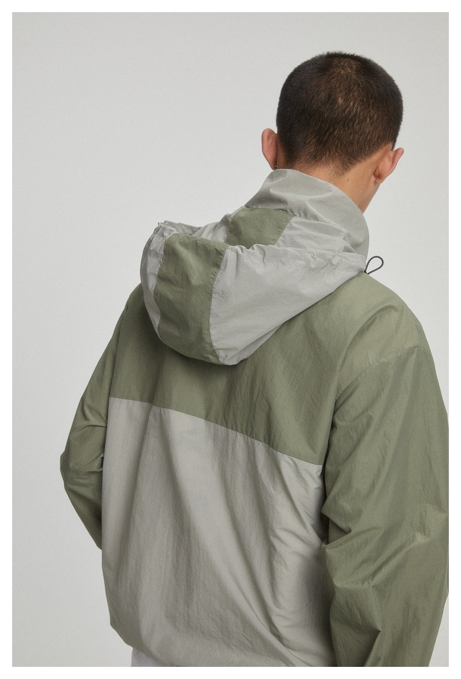 Close back view of the olive and light gray color-block jacket and its hood.