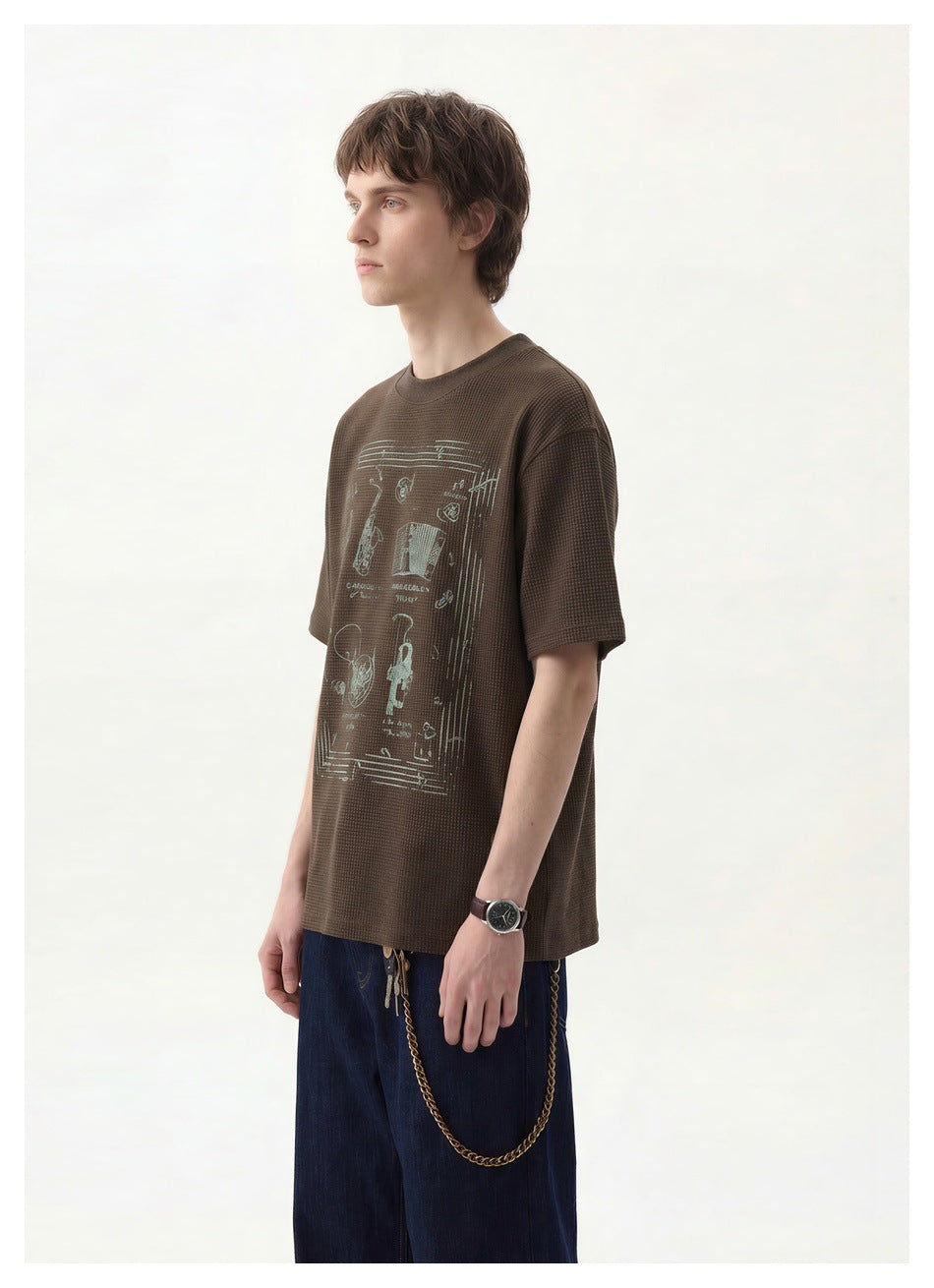 Closer view of a model wearing a dark brown T-shirt with a pale illustrated front graphic.