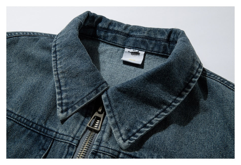 Blue denim jacket collar and neck label shown with part of the front zipper.