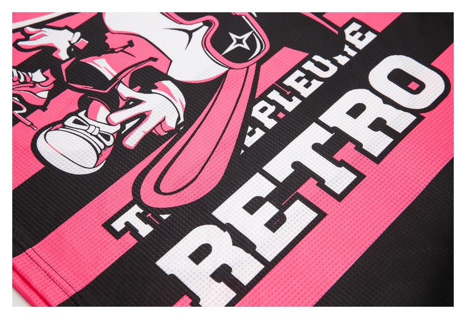 Close-up of a black and hot-pink garment graphic with a cartoon figure and large white lettering.