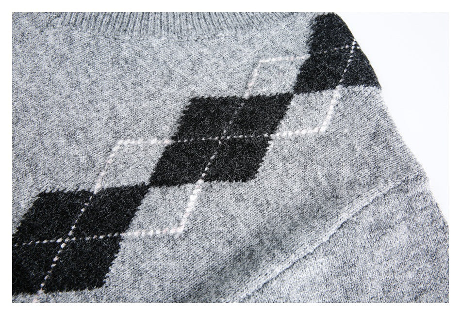 Close-up of a gray marled sweater sleeve with black argyle diamonds outlined by pale stitching.