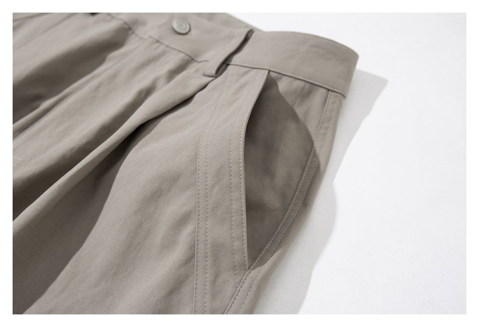 Angled close-up of taupe cargo pants showing the waistband and stitched front pocket opening.