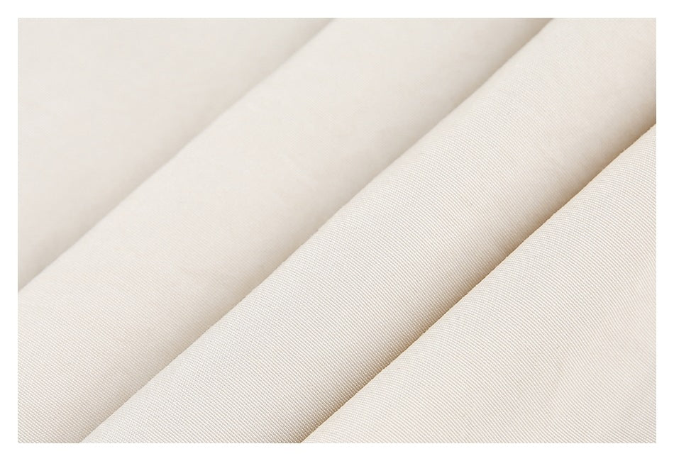 Close-up of light beige fabric arranged in folds, showing its fine surface texture.