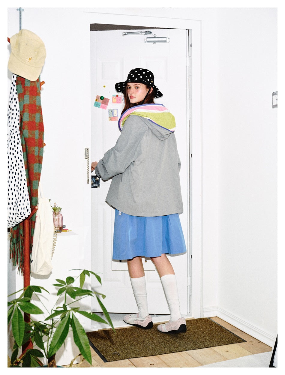 Model turned to show the back of a gray hooded jacket with colorful hood lining.