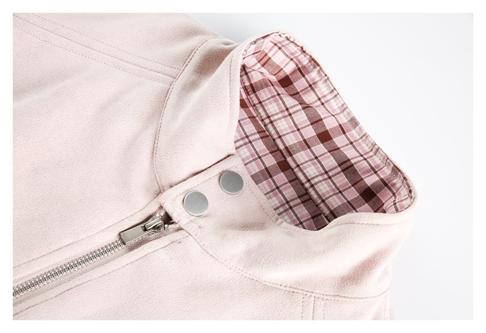 Close-up of a pale pink jacket with a plaid-lined hood or collar, metal snaps, and a zipper.