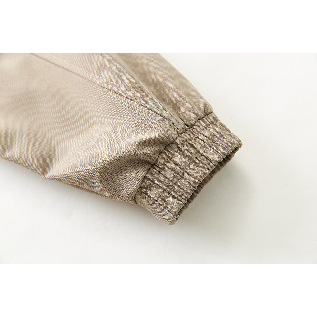 Close-up of a beige jacket sleeve ending in a gathered elastic cuff.
