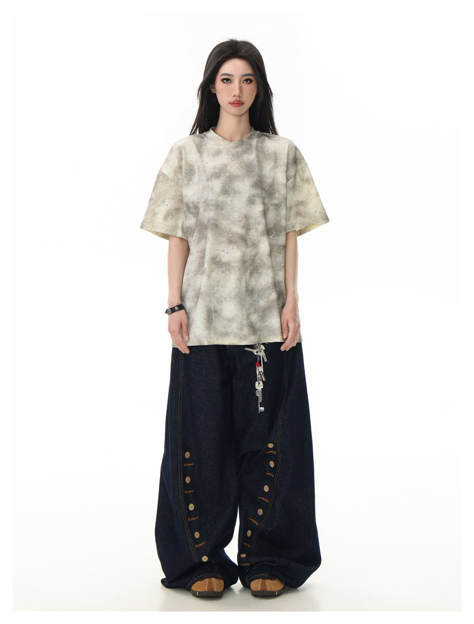 Model wearing the beige tie-dye splatter T-shirt with wide-leg dark denim jeans, full-length front view