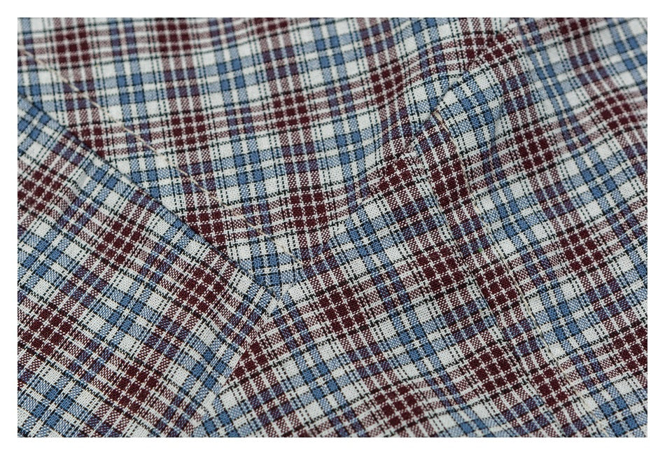 Close-up of blue, burgundy, and white plaid shirt fabric with a stitched seam.