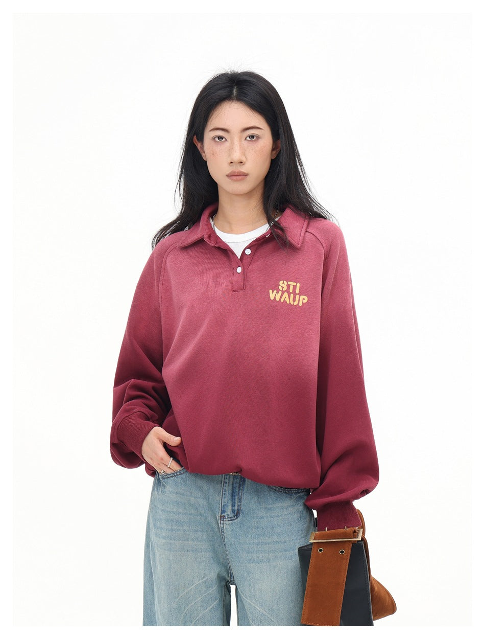 Close front view of a model wearing a rose-red collared pullover with a short button placket and yellow chest lettering.