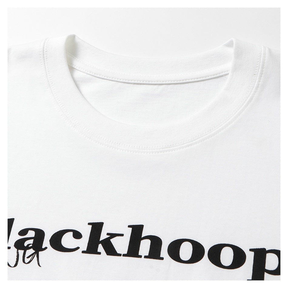 Close-up of a white T-shirt's ribbed crew neck and cropped black chest lettering.