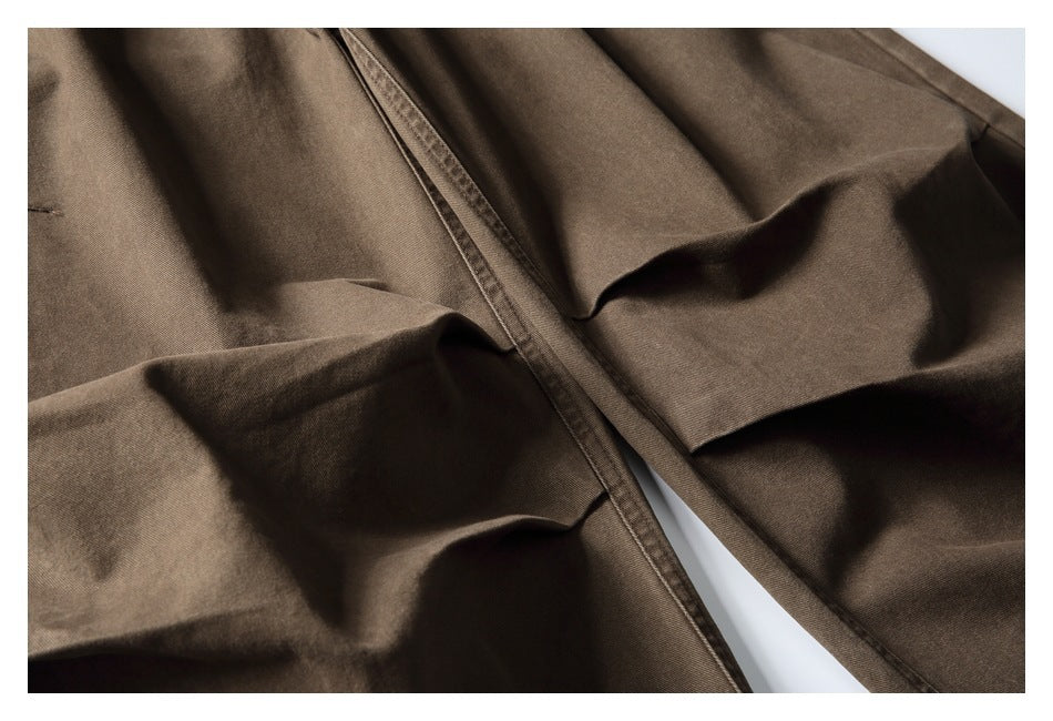 Close-up of brown trouser fabric and stitched seams, with the garment loosely folded.